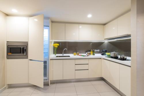 a kitchen with white cabinets and a refrigerator at Ascott Sentral Kuala Lumpur in Kuala Lumpur