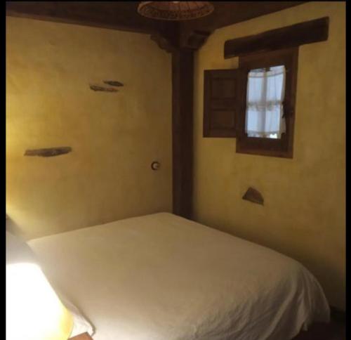 a bedroom with a white bed and a window at Hotel Rural La Fuente in Patones