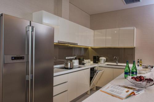 a kitchen with a refrigerator and a bowl of fruit on a counter at Ascott Sentral Kuala Lumpur in Kuala Lumpur