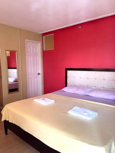 a bedroom with a large bed with a red wall at Winland Tower 1 Condominium in Cebu City