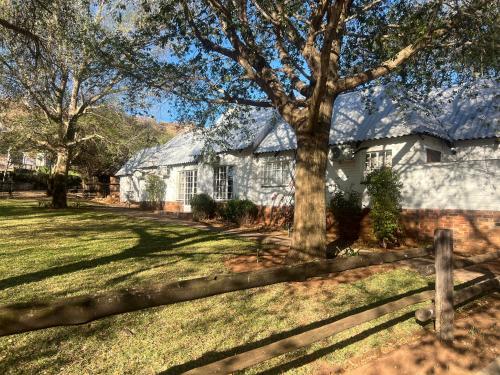 a white house with a tree and a fence at Die Stalle in Klerksdorp