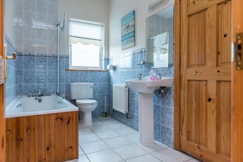 a bathroom with a sink and a toilet and a tub at Portbeg Holiday Homes at Donegal Bay in Bundoran