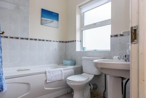 a white bathroom with a toilet and a sink at Ocean View - 2 Bedroom Townhouse in Bundoran