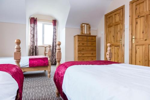 a bedroom with two beds and a dresser at Portbeg Holiday Homes at Donegal Bay in Bundoran