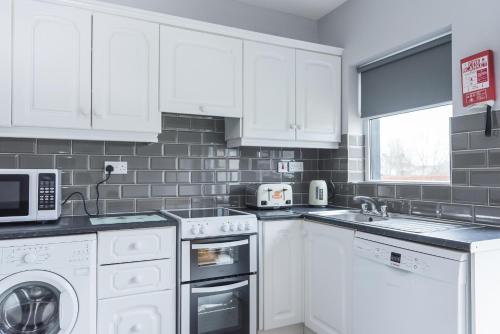 a white kitchen with white cabinets and appliances at Bunhovil -3 bedroom in Bundoran