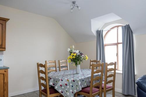 a dining room table with a vase of flowers on it at Atlantic Point Sea View Apartment in Bundoran