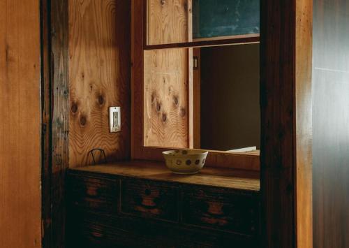 a bathroom with a mirror and a bowl on a dresser at JUU arts&stay nishikujo-osaka in Osaka
