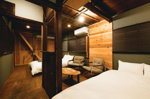 a bedroom with a bed and two chairs in it at JUU arts&stay nishikujo-osaka in Osaka