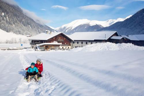 two people sitting on a snow pulled sled in the snow at Aussermahrhof - familyfarm in Gsies