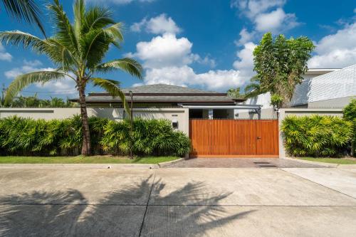 a house with a wooden gate and palm trees at Peykaa Estate Pool Villa by HCR in Phuket Town