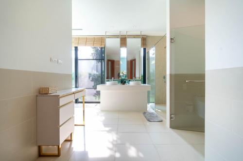 a bathroom with a tub and a sink and a mirror at Peykaa Estate Pool Villa by HCR in Phuket Town