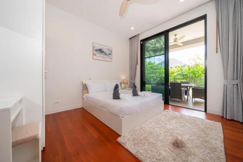 a living room with a white couch and a large window at Peykaa Estate Pool Villa by HCR in Phuket Town