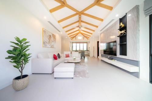 a living room with a white couch and a tv at Peykaa Estate Pool Villa by HCR in Phuket Town
