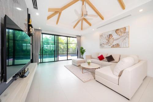 a living room with a white couch and a tv at Peykaa Estate Pool Villa by HCR in Phuket Town
