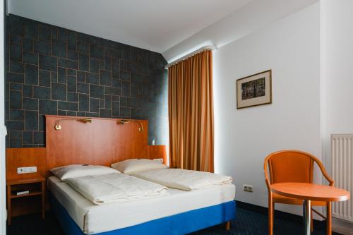 a bedroom with a bed and a table and a chair at Hotel Mirage in Duisburg
