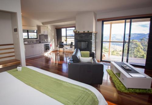 a bedroom with a bed and a living room at Blue Summit Cottages in Maleny