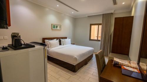 a hotel room with a bed and a desk at Hadiqat Lina Serviced Apartments Al Khobar in Al Khobar