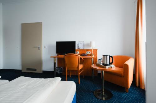 a hotel room with a bed and a desk with a computer at Hotel Mirage in Duisburg