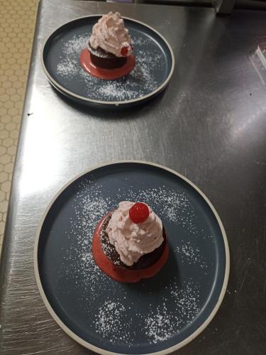 two black plates with desserts on them on a counter at La Sapinière St Lary Soulan in Saint-Lary-Soulan