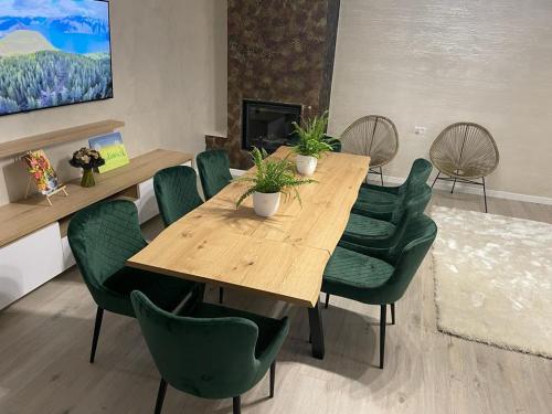 a dining room with a wooden table and green chairs at Mountain Lake JBS in Focşani