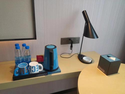 a desk with a coffee maker and a lamp on it at Echarm Hotel Fengcheng Fengshui Lake in Sunjiadu
