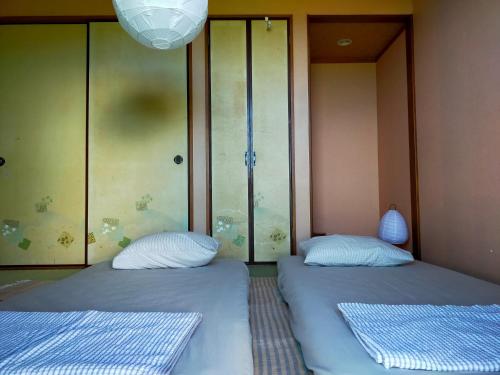 two beds sitting next to each other in a room at 奄美ゲストハウス宇宿サンライズビーチ in Amami