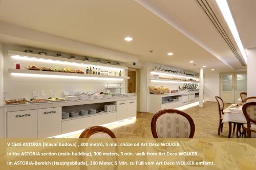 a kitchen with white cabinets and a table and chairs at Art Deco WOLKER by ASTORIA Hotel & Medical Spa in Karlovy Vary