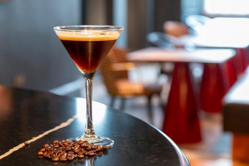 a drink in a glass sitting on a table with coffee beans at Hotel Indigo Edinburgh by IHG in Edinburgh