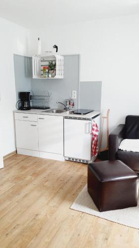 a kitchen with white cabinets and a sink and a couch at Ferienwohnungen Naturzeit in Willingen