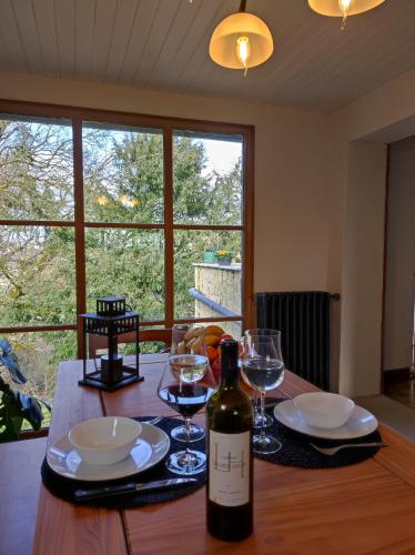 - une bouteille de vin assise sur une table en bois avec des verres dans l'établissement La Ferme aux Hibiscus, à Sarlat-la-Canéda