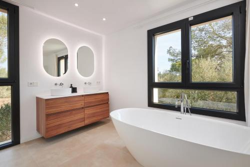 a white bathroom with a tub and two windows at Finca Ses Rotes in Cala Ferrera
