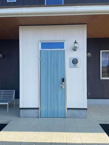a blue door on the side of a building at かなわアパートメントステイ201 in Tsuruga