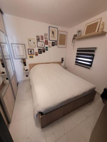 - une chambre avec un lit dans une pièce avec des photos sur le mur dans l'établissement Agreable et Calme 3 pieces Terrasse, Piscine, Tennis, Plage, à Vallauris