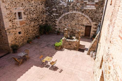 an outdoor patio with chairs and tables in a stone building at Agroturisme Sant Dionis in Campllong