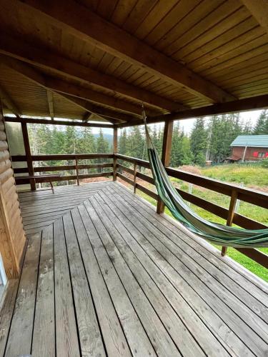 a hammock on a wooden deck with a fence at Cabana dintre brazi in Muntele Băişorii