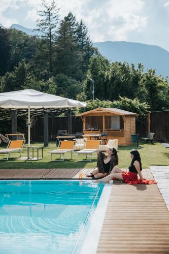 two women sitting next to a swimming pool at B&B Toblerina in Ascona