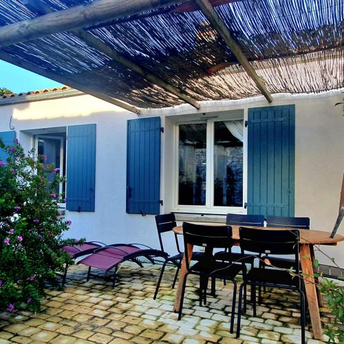 un patio avec une table et des chaises sous une pergola dans l'établissement Villa Margot, à Saint-Pierre-dʼOléron