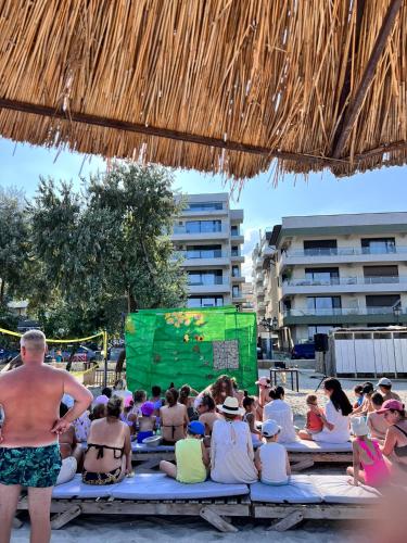 a group of people sitting on benches under a straw umbrella at Hotel Manor in Mamaia Nord