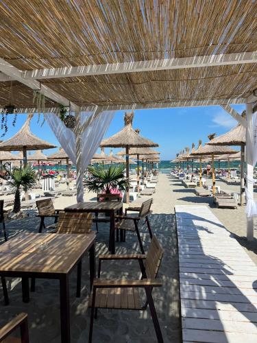a beach with tables and chairs and straw umbrellas at Hotel Manor in Mamaia Nord