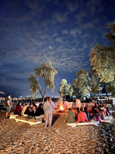 a large group of people sitting around a fire at Hotel Manor in Mamaia Nord