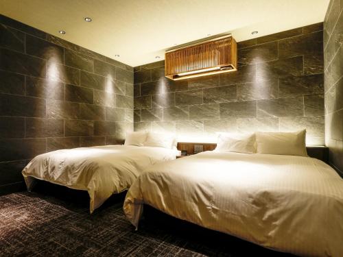 two beds in a hotel room with white sheets at FIVE SPRING RESORT THE SHIRAHAMA in Shirahama