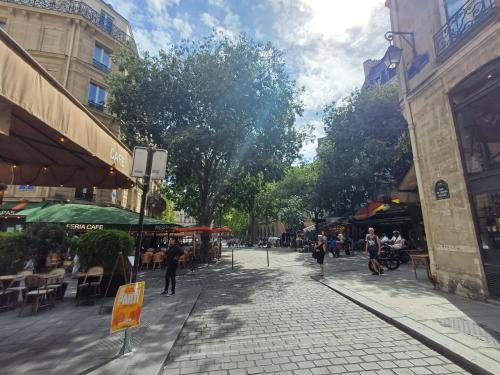 a cobblestone street with tables and chairs in a city at Happy Stay Paris - Suite Hotel de Ville le Marais in Paris