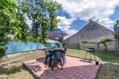 un patio avec une table, des chaises et un parasol dans l'établissement L'échappée Belle, à Romorantin-Lanthenay