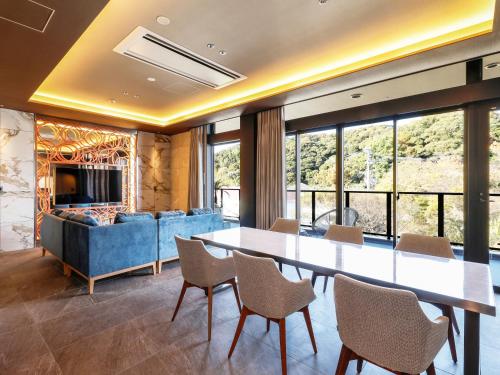 a dining room with a table and chairs and a couch at FIVE SPRING RESORT THE SHIRAHAMA in Shirahama