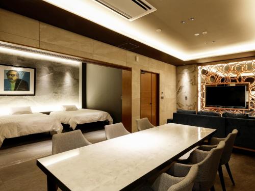 a hotel room with two beds and a table and chairs at FIVE SPRING RESORT THE SHIRAHAMA in Shirahama