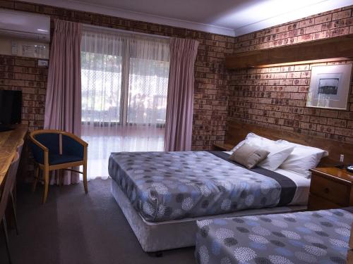 a hotel room with two beds and a desk and a window at Ten Dollar Town Motel in Gulgong
