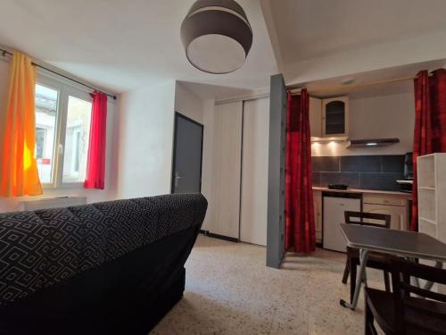 un salon avec un canapé et une table et une cuisine dans l'établissement Studio meublé, à Lunel