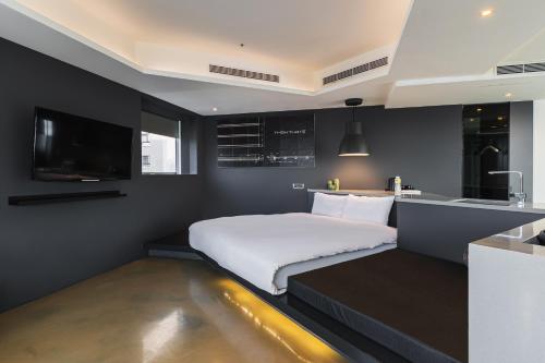 a bedroom with a white bed and a kitchen at CHECK inn Taichung Liming in Taichung