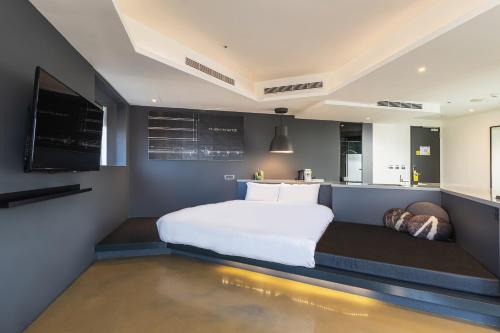 a bedroom with a large white bed and a kitchen at CHECK inn Taichung Liming in Taichung