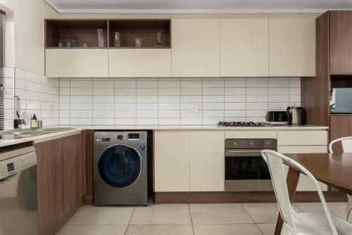 a kitchen with a washing machine and a table at Waters Edge Apartments in Cape Town